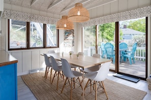 Un comedor con una mesa de madera, sillas blancas y vistas a la terraza.
