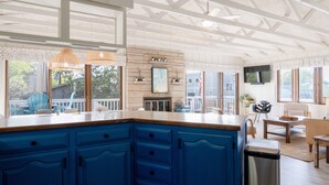 Een keuken met blauwe kastjes, een houten aanrecht, een open haard en een aan de muur bevestigde televisie.