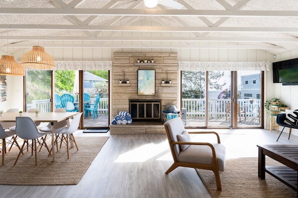 Un espacio habitable amplio con chimenea, ventanas grandes y una mesa de comedor.