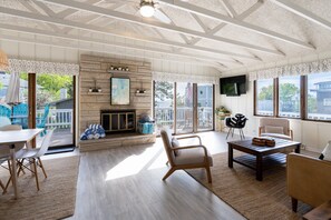 Un amplio salón con chimenea, asientos cómodos y ventanas grandes que ofrecen vistas al exterior.