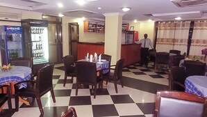 Un restaurante con piso a cuadros, mesas con manteles azules y un refrigerador de Pepsi.
