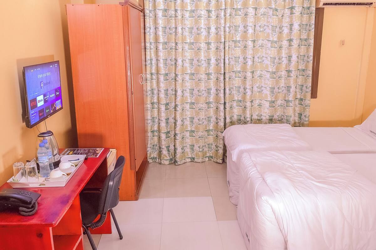 Een hotelkamer met een bed, een bureau met een computer, een telefoon en een kledingkast.