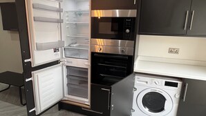 A compact kitchen with a built-in microwave, oven, and washing machine. - Stylish Flat in London, sleeps 4
 (Hornchurch)