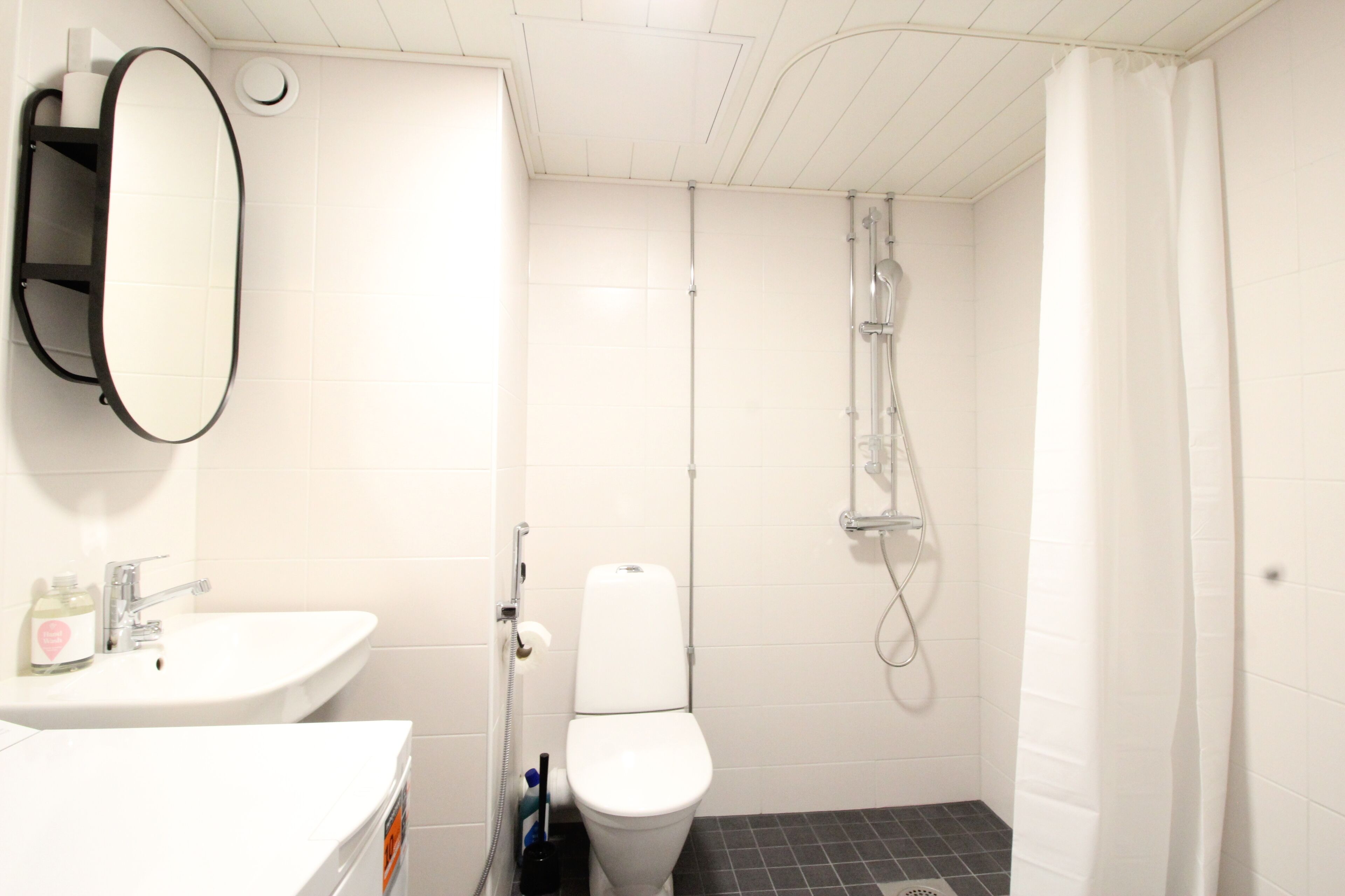 Un baño con lavamanos, inodoro y ducha blancos.