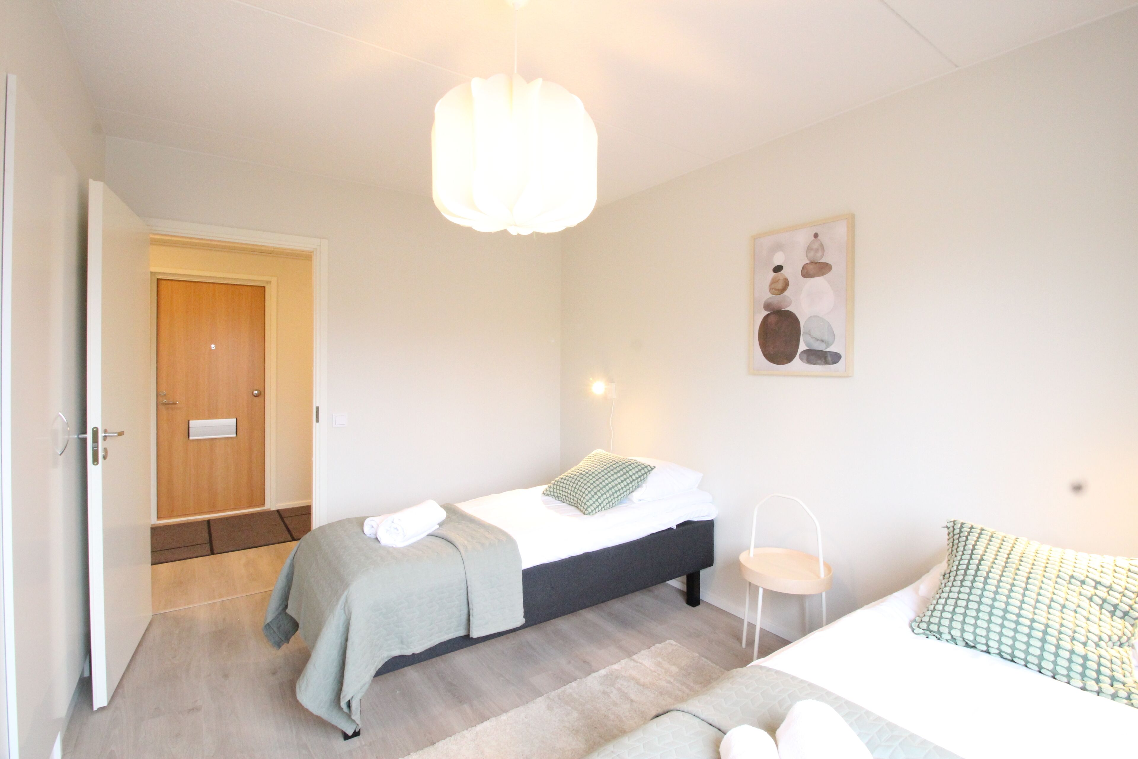 Une chambre à coucher comprenant un lit, une table de chevet et une porte donnant sur une autre pièce.