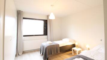 Un dormitorio con dos camas, una ventana, un radiador y lámparas de noche.