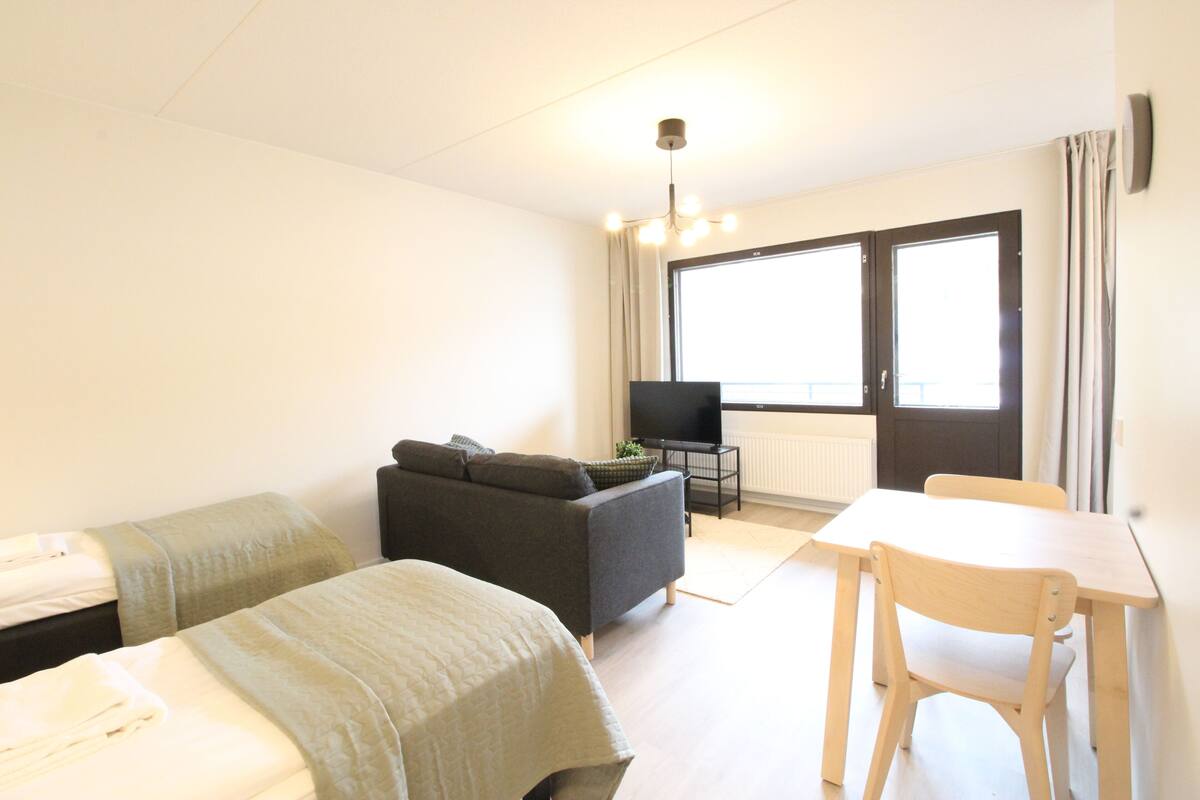 A hotel room with a bed, a sofa, a TV, and a dining table.