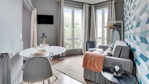 Une pièce moderne avec une table à manger ronde, un canapé et un téléviseur fixé au mur.