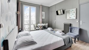Une chambre d’hôtel équipée d’un lit, d’un bureau, d’une chaise, d’une télévision et d’un balcon avec vue.