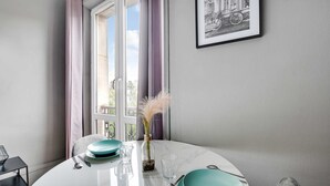 Une table à manger avec des assiettes de couleur turquoise, un verre transparent et un vase contenant des fleurs séchées.