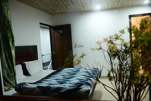 Ein Schlafzimmer mit einem Bett, einem hölzernen Kopfteil, einer Tür mit der Nummer 102 und einem Spiegel an der Wand.