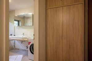 Een badkamer met een houten kast, een wastafel en een wasmachine.
