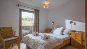 Una camera d'albergo con un letto, una sedia, un comodino, una lampada e vista sull'esterno.