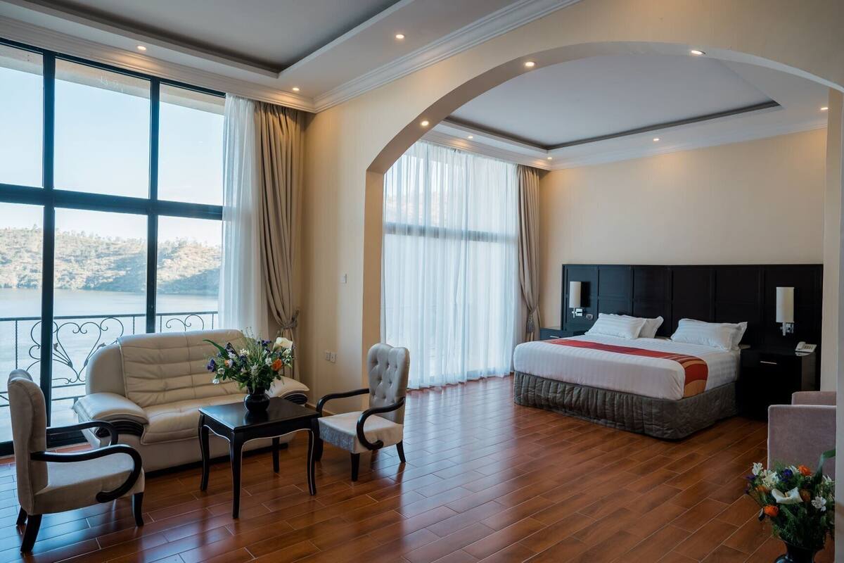 Habitación de hotel con una cama grande, un sofá, una mesa de comedor y vistas al exterior.