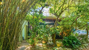 A garden area with a statue, potted plants, and a sign indicating restricted access. - Zen Studio at Lotus Garden Cafe (Panama City Beach)