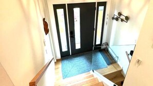 A staircase with wooden flooring leading to a door with a black frame. - Creekside Haven Family-Friendly Squamish Home (Squamish)