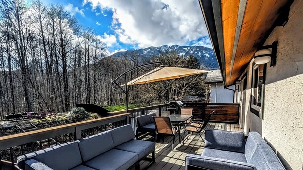 A deck with outdoor furniture, a barbecue grill, and a view of mountains. - Creekside Haven Family-Friendly Squamish Home (Squamish)