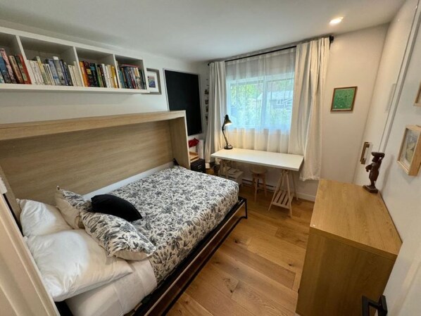 A bedroom with a bed, a desk, and a bookshelf.