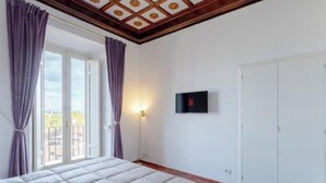 A bedroom with a bed, a TV mounted on the wall, and a sliding door leading to an outdoor area. - Authentic Architectural Gem in the Heart of Rome
 (Roma)