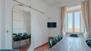 A conference room with a large table, chairs, a TV, and a window with curtains. - Authentic Architectural Gem in the Heart of Rome
 (Roma)
