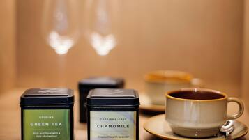 Un juego de té con una taza y platillo, dos latas de té y dos vasos.