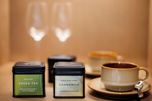 Un juego de té con una taza y platillo, dos latas de té y dos vasos.