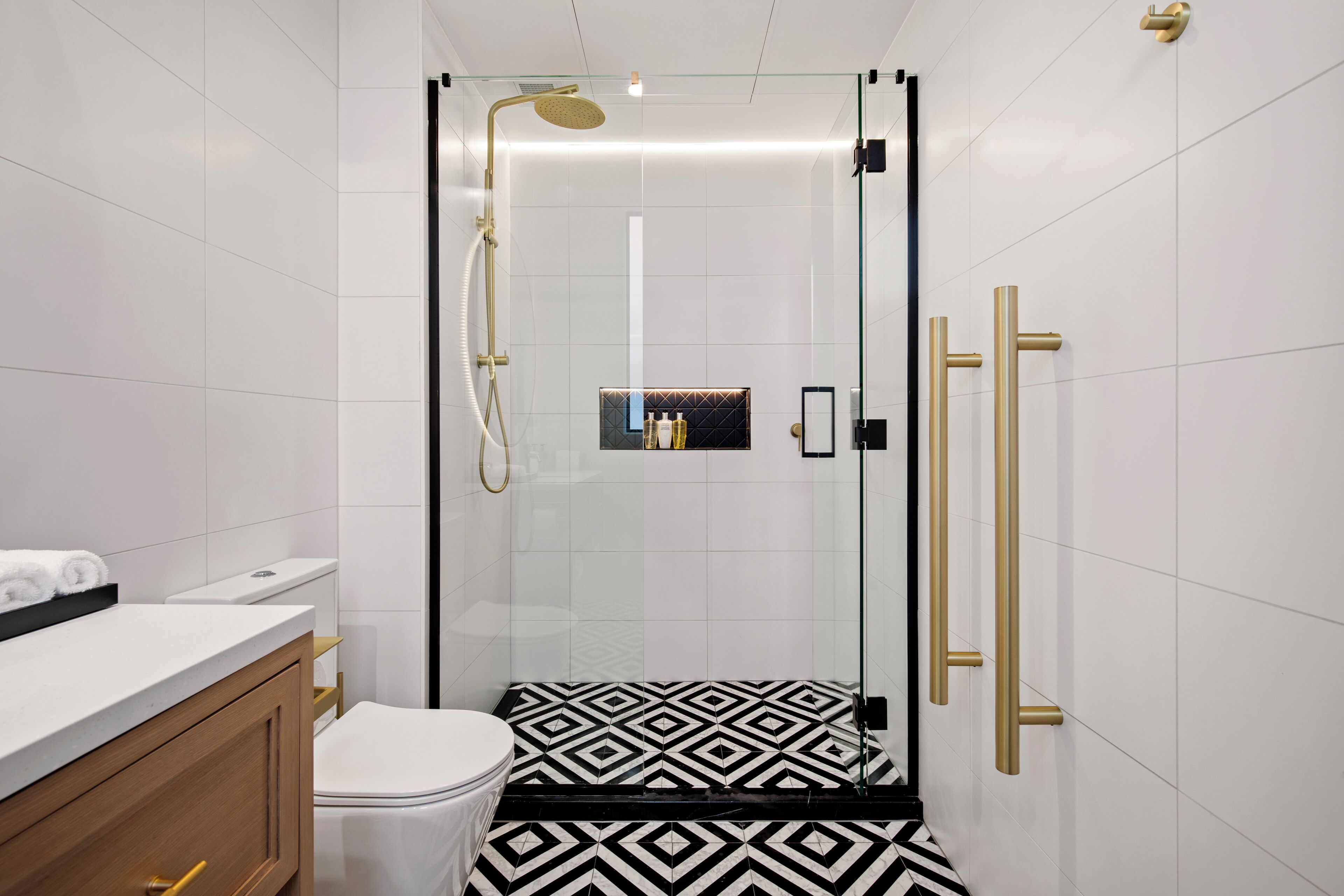 A modern bathroom with a glass-enclosed shower, a toilet, and a vanity with a white countertop.