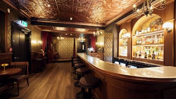 A bar area with a wooden bar counter, stools, and a well-stocked liquor shelf.