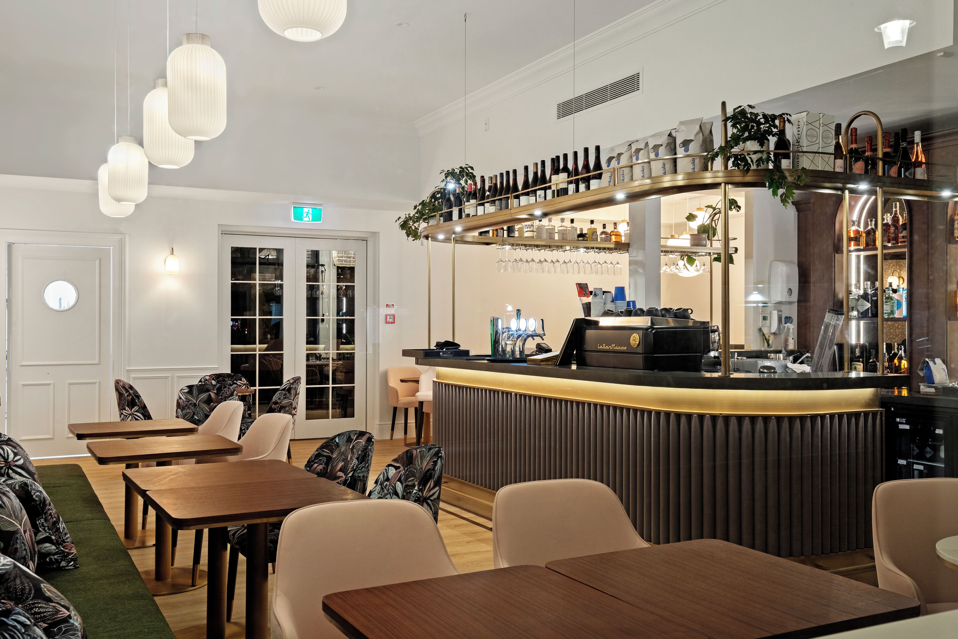A restaurant with a bar area, wooden tables, and chairs.