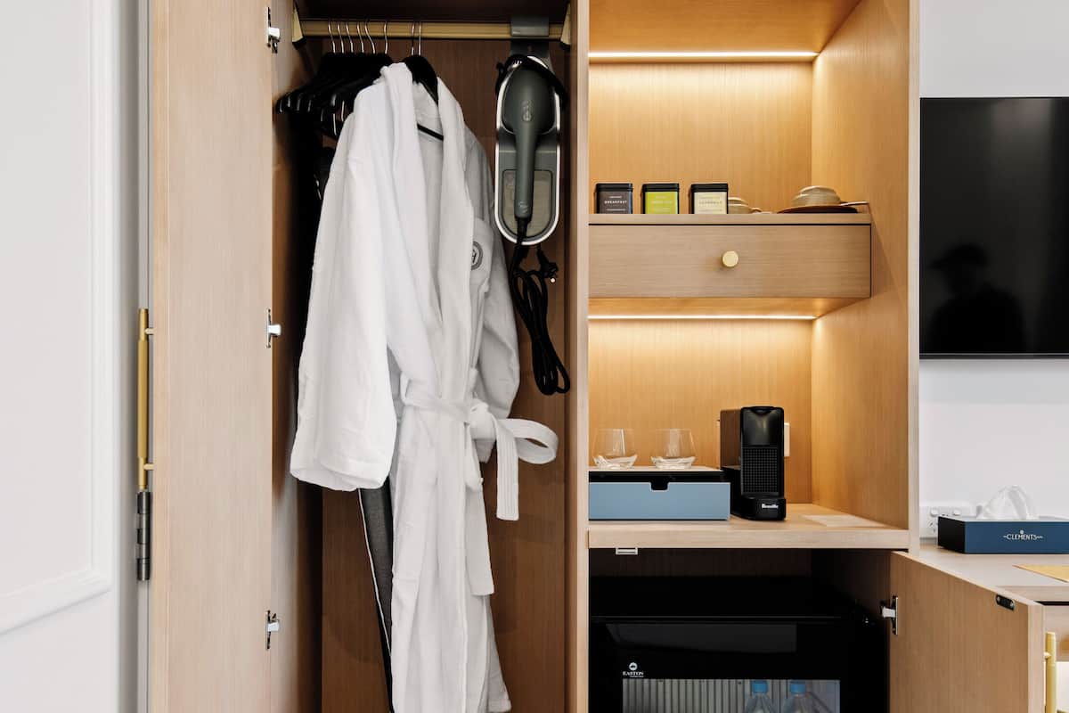 Ein begehbarer Kleiderschrank mit Bademantel, Schuhen und einer Kaffeemaschine.