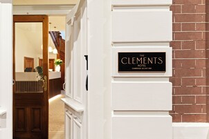 Entrada de un hotel con un cartel que dice 'The Clement Hotel' y una pared de ladrillo.