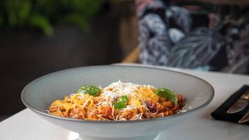 A bowl of pasta with cheese and basil on a table.