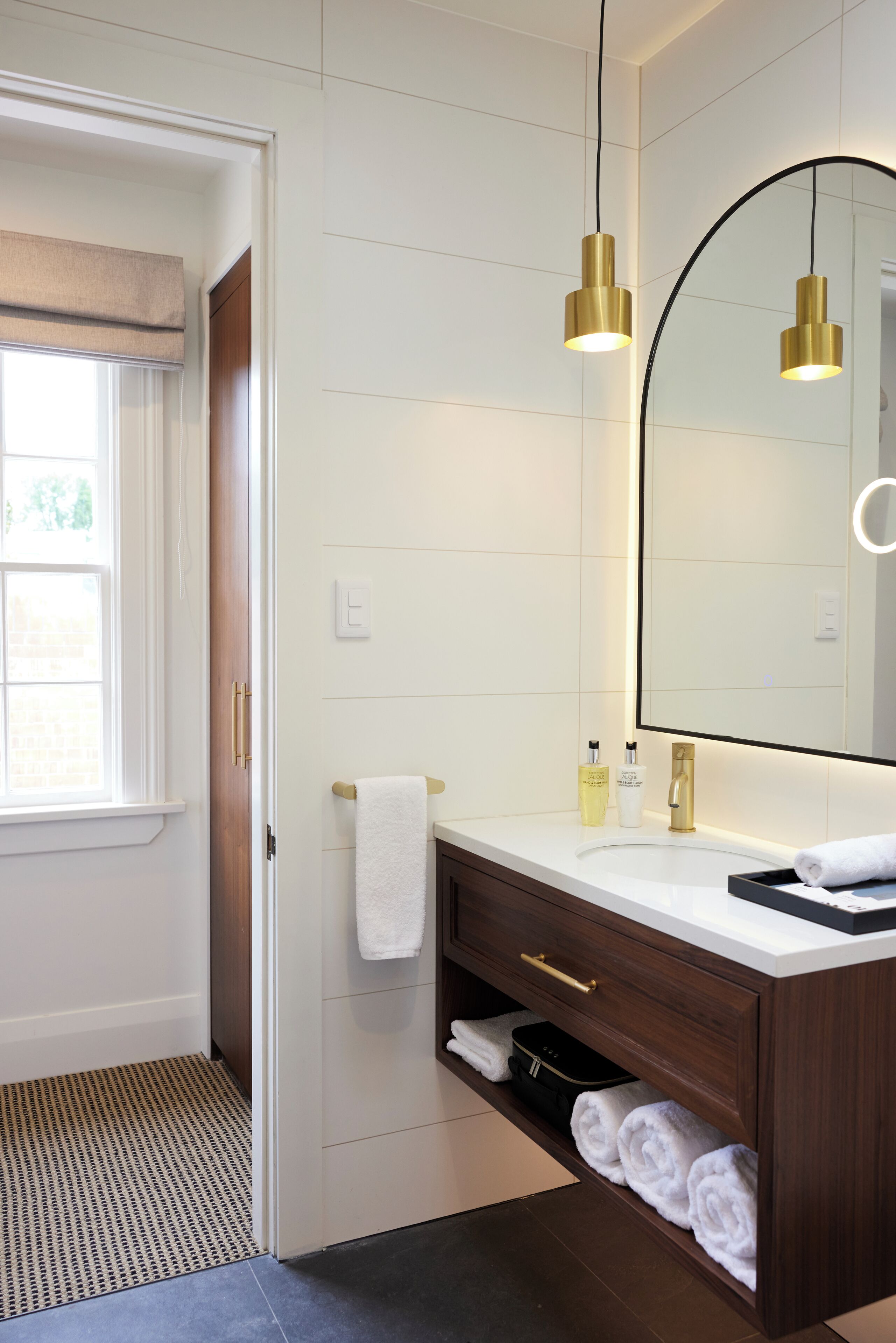 Un baño moderno con tocador blanco, detalles dorados y un espejo grande.
