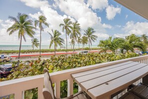 A balcony with a view of the beach, palm trees, and a road with cars. - A Sunkissed Bungalow-B205 (Key West)