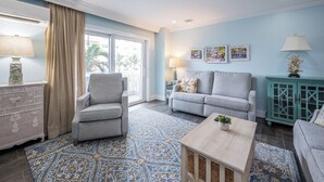 A living room with a sofa, armchair, coffee table, and a teal cabinet.