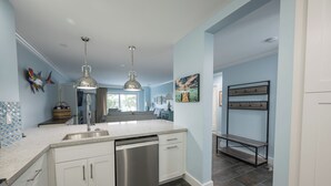 A modern kitchen with white cabinets, stainless steel appliances, and a large island.