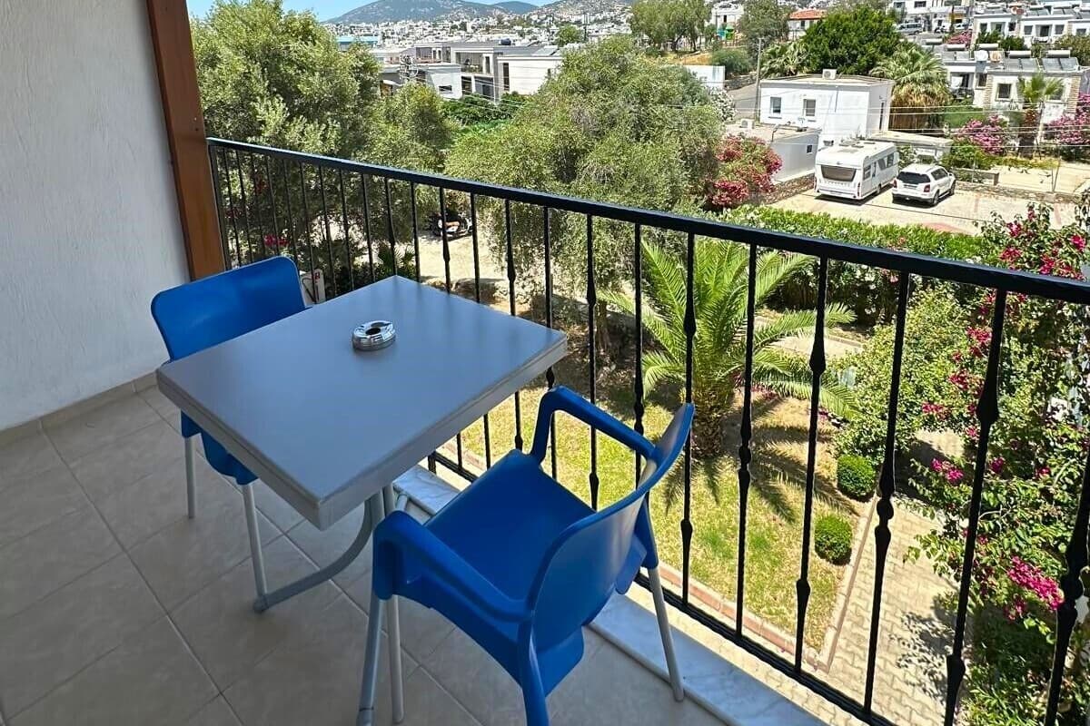 A balcony with a table and chairs, overlooking a residential area with houses and greenery.