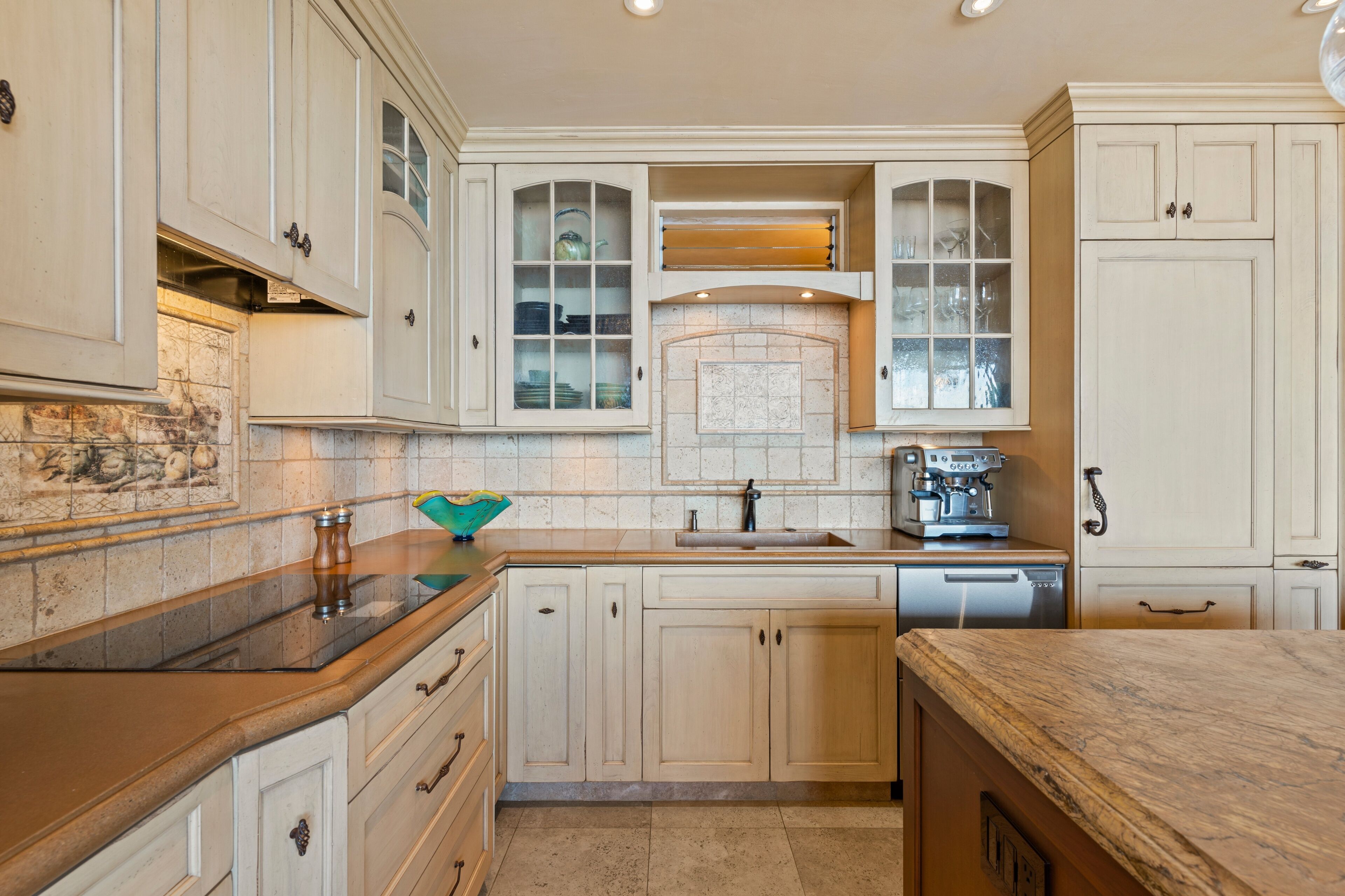 A kitchen with white cabinetry, a marble countertop, and a coffee machine.
