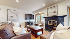 A living room with a fireplace, a TV mounted on the wall, and a large abstract painting.