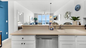 A modern kitchen with a dishwasher, a sink, and a large window offering a view of the ocean. - ☀️Beachfront|Gulf Views|Pools|3BR Summerwind 1203☀️ (Navarre Beach)