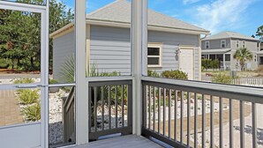 A residential building with a grey exterior, white trim, and a balcony with a railing.