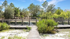 A wooden boardwalk leading to a pond with a wooden fence and trees.