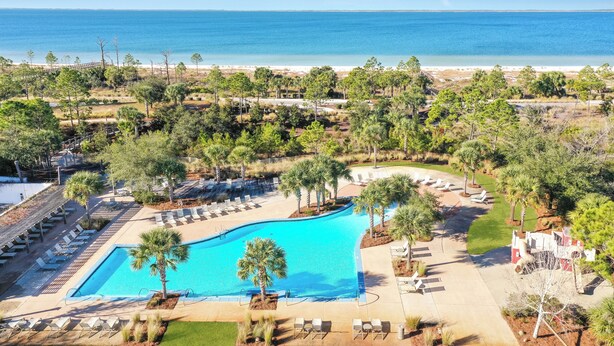 A resort with a large pool, lounge chairs, and a view of the ocean.