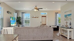 A living room with a sofa, a coffee table, a TV, and a ceiling fan.