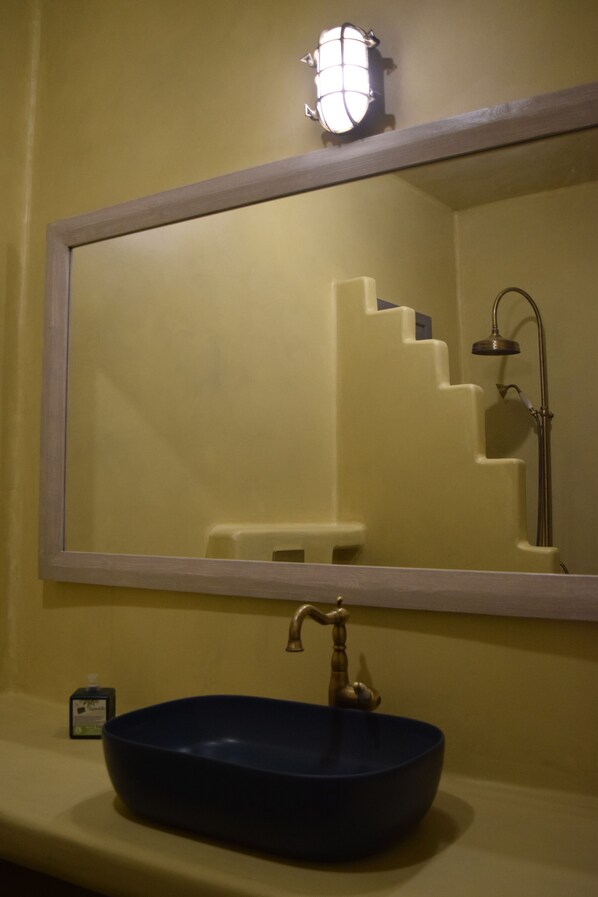 Une salle de bain avec un grand miroir, un lavabo bleu et une douche.