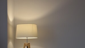 Lattiavalaisin, jossa on valkoinen varjostin, vihreä sohva ja puinen pöytä.