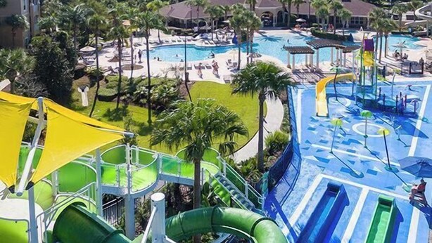 Ein Wasserpark mit mehreren Rutschen und Pools, umgeben von Palmen und Hotelgebäuden.