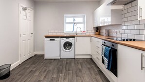 A compact kitchen with a washing machine, oven, and a window.
