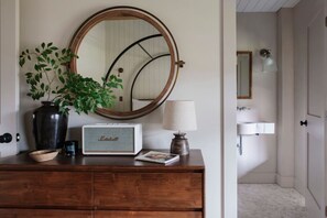 Un aparador de madera con espejo, una radio, una lámpara y una planta en maceta.