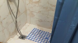 Une salle de bain avec un espace douche, un rideau de douche bleu et un sol carrelé.